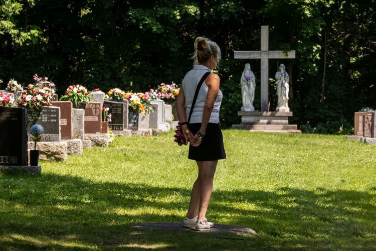 Trauernde Frau auf dem Friedhof.